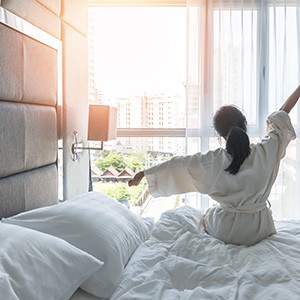 Woman sitting in bed and stretching in morning