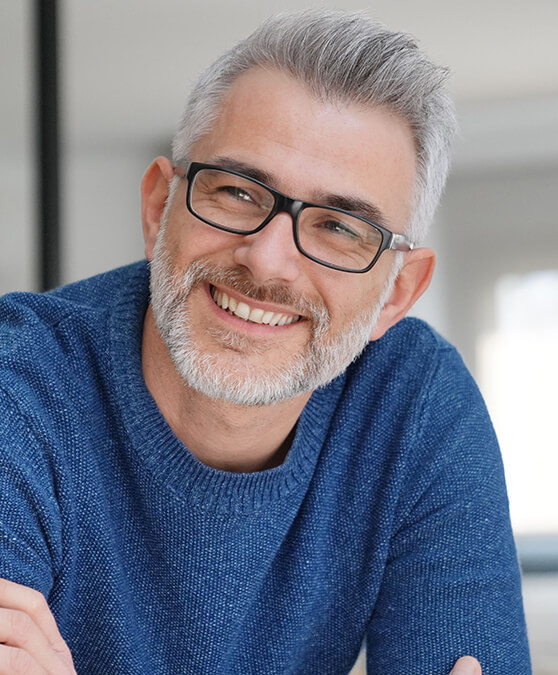 Man with sweater and glasses leaning forward and smiling