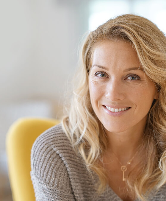 Woman in sweater sitting in yellow chair and smiling