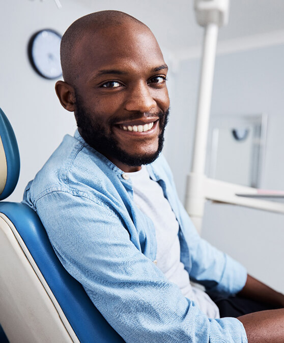 Man with beard sitting in dental chair and smiling