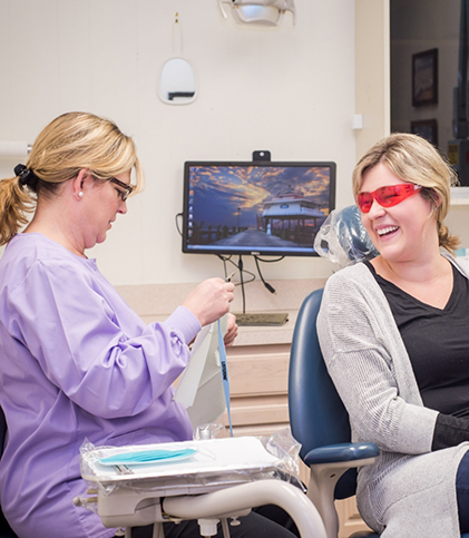 Dental team member preparing for fluoride treatment while patient watches